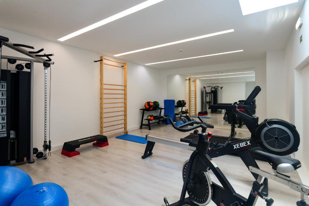 A bright fitness room with cardio machines, weights, mats, and wall bars.