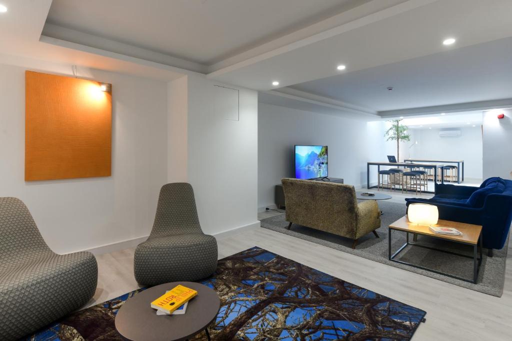 A contemporary shared lounge with upholstered chairs, a television and a communal table.