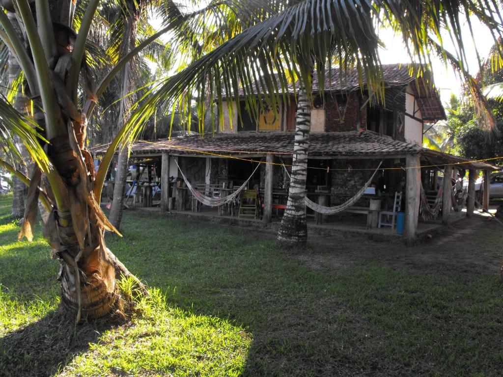 a building with a palm tree in front of it at Hospedaria Cumuruxatiba in Cumuruxatiba