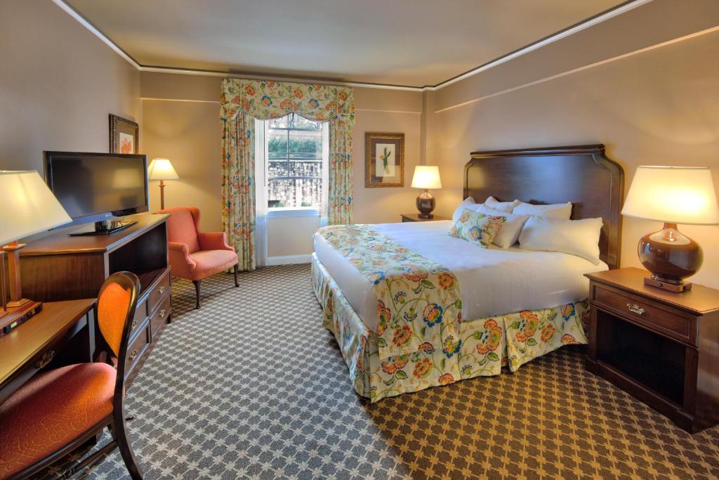 a hotel room with a bed and a desk and a television at Menger Hotel in San Antonio