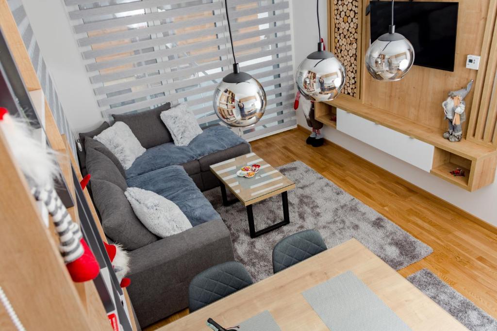 een woonkamer met een grijze bank en een tafel bij Apartman Amsterdam Jahorina in Jahorina