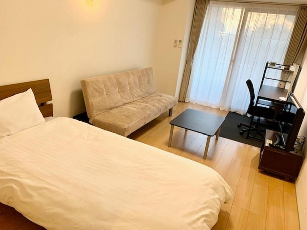 a bedroom with a bed and a chair and a table at Hamamoto Palace Taniyama - Vacation STAY 10397 in Kagoshima