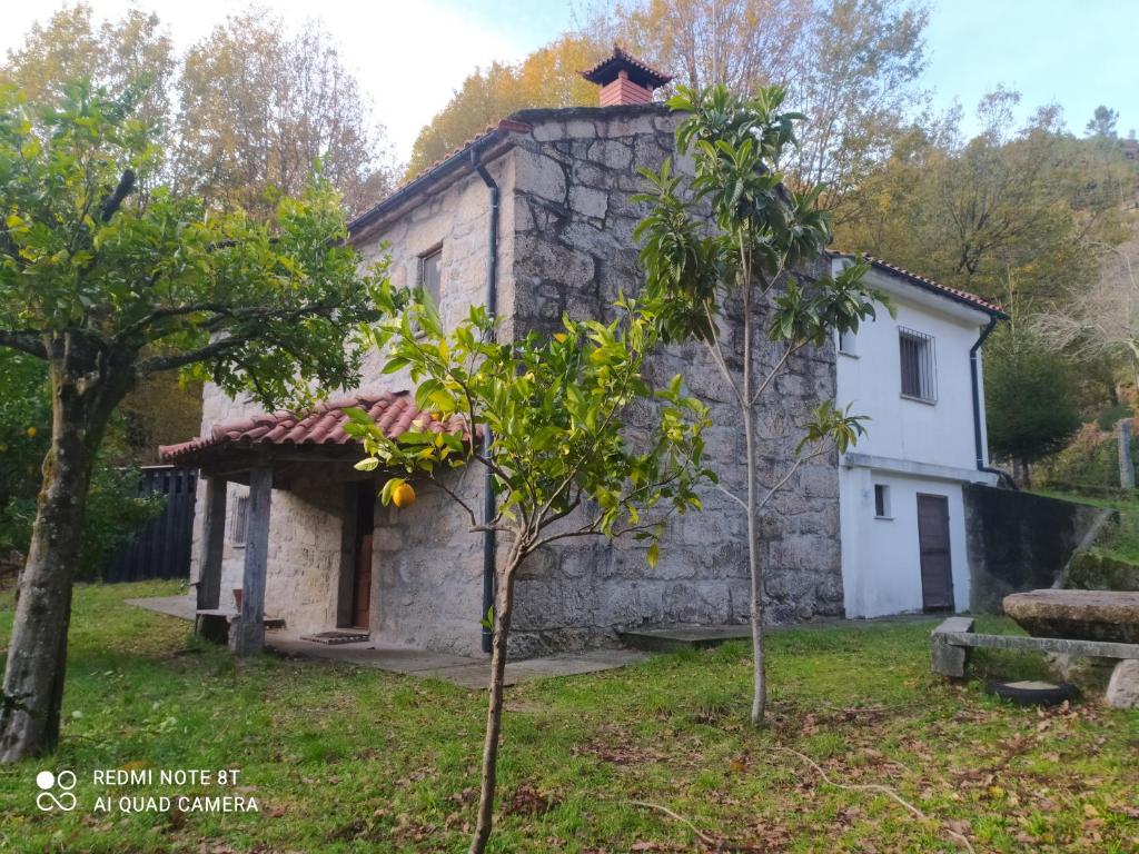 una vieja casa de piedra con árboles delante de ella en Casa Prado de Mó en Arcos de Valdevez