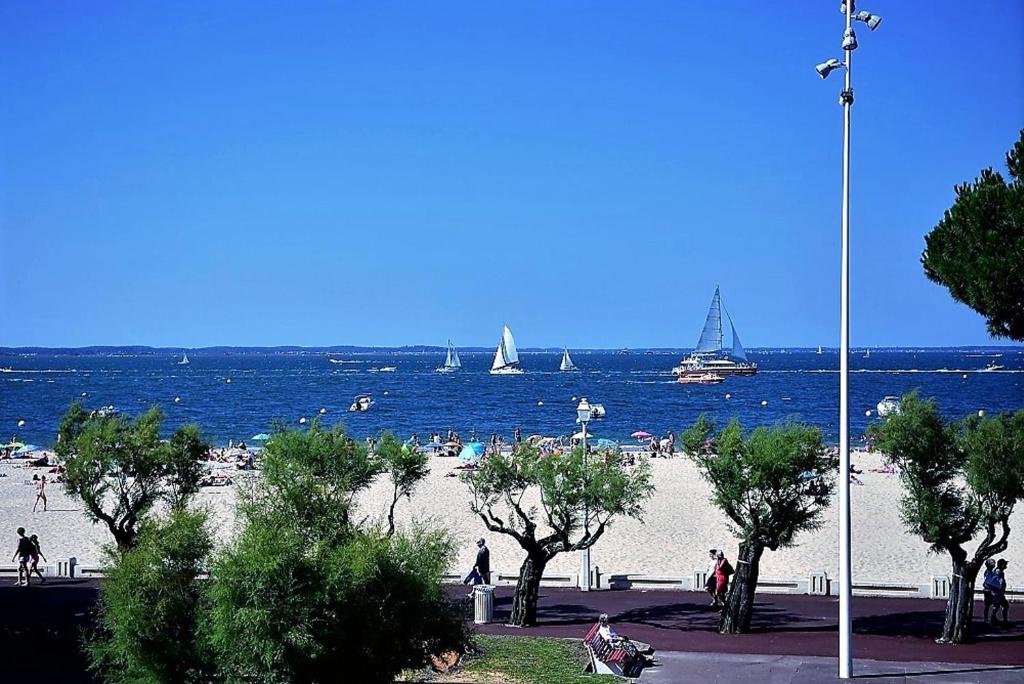 een strand met mensen en boten in het water bij Studio avec vue sur la mer et balcon amenage a Arcachon in Arcachon