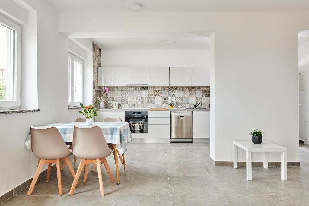 a white kitchen with a table and chairs at Apartmani Ivana in Umag