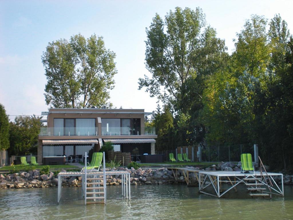 una casa en el agua con un muelle y sillas en Aba Sea House en Balatonszárszó