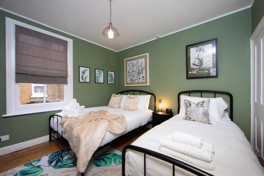 Dos camas en una habitación con paredes verdes. en The Victorian Getaway - Central, en Canterbury