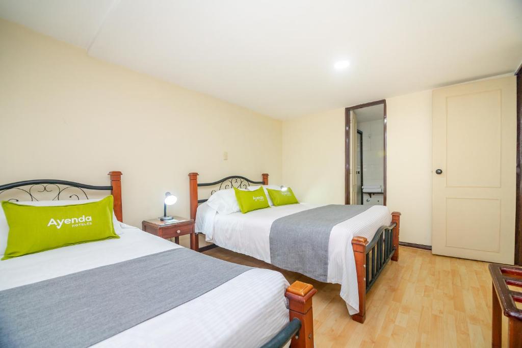 - 2 lits dans une chambre d'hôtel avec des oreillers verts dans l'établissement Ayenda Aragon, à Manizales