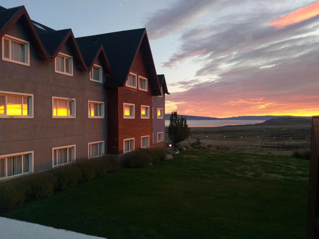 un edificio con la puesta de sol en el fondo en Alto Calafate Hotel en El Calafate