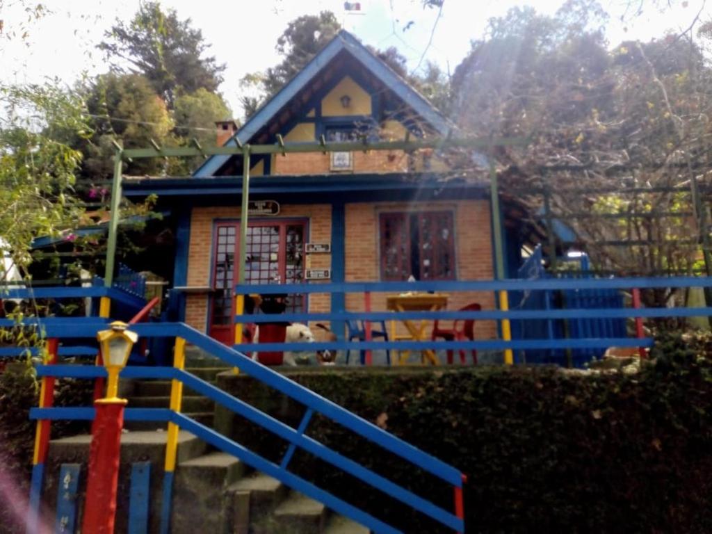 a house with a blue fence in front of it at Casa do Passarinho in Campos do Jordão