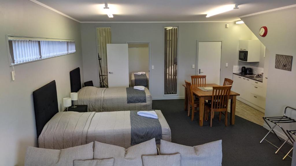 a hotel room with two beds and a table and a kitchen at Cozy one bedroom apartment near Auckland Airport in Auckland