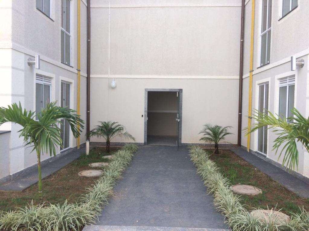 a hallway leading to a building with palm trees at Apartamento Gaia in Campos dos Goytacazes
