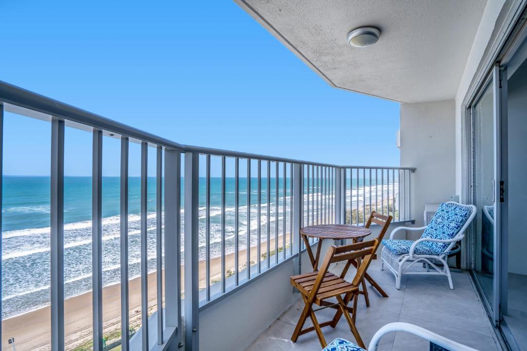 a balcony with a table and chairs and the ocean at Pacific Plaza Apartments in Gold Coast
