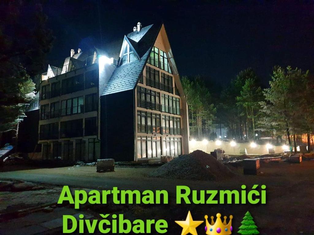 un grand bâtiment la nuit avec les mots apartment rijenstein istg divergence dans l'établissement Apartman Ruzmići Divčibare, à Divčibare