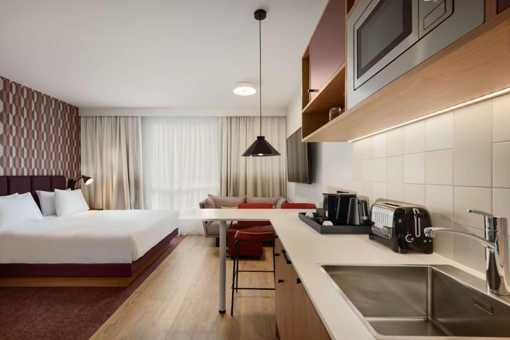 a hotel room with a bed and a kitchen at Hyatt House Paris Charles de Gaulle Airport in Roissy-en-France