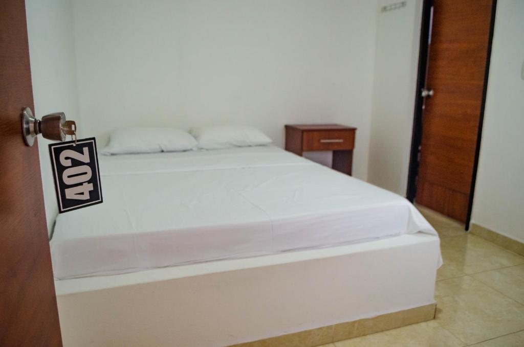 um quarto com uma cama branca com um cartaz em Hotel Central Fusa em Fusagasugá