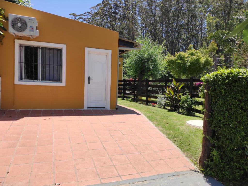 a yellow house with a white door in a yard at Ybá Pitá in Colonia del Sacramento