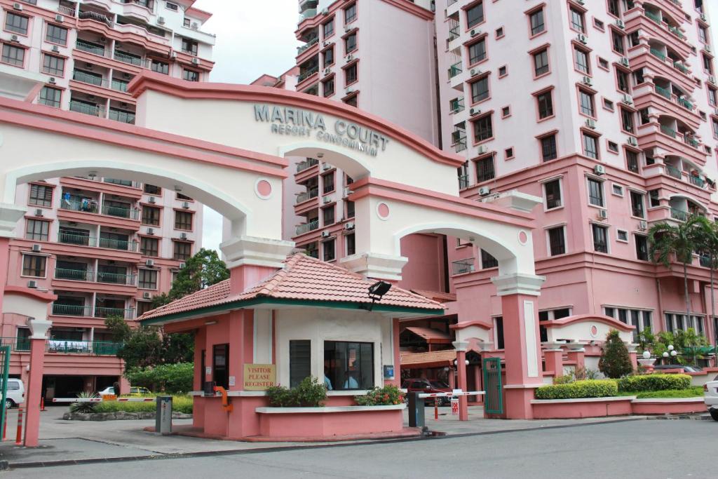 een roze gebouw voor enkele hoge gebouwen bij Marina Court Kk City Homestay in Kota Kinabalu