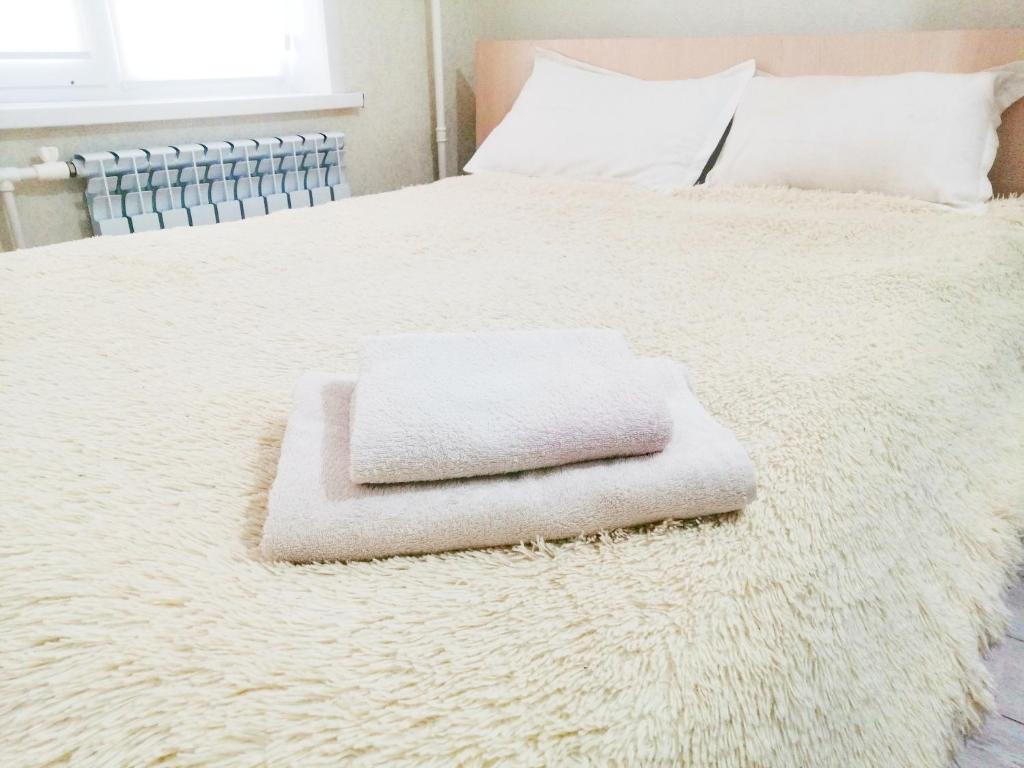 un letto bianco con un asciugamano sopra di Уют в Авангарде a Atyraū