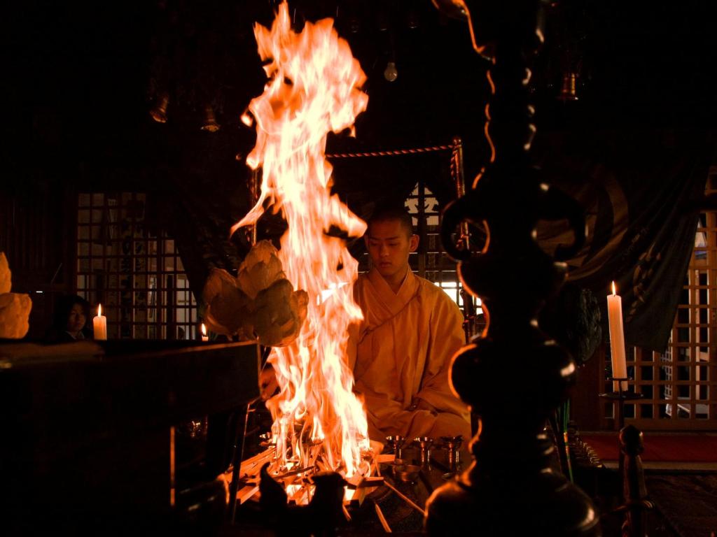 Un homme est assis devant un feu dans l'établissement 高野山 宿坊 恵光院 -Koyasan Syukubo Ekoin Temple-, à Koyasan