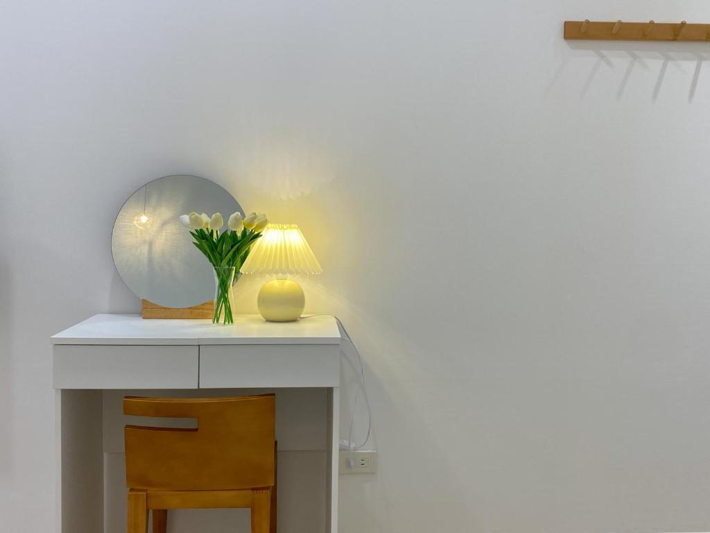 a table with a vase of flowers and a lamp at 羅東微風小棧民宿 in Luodong