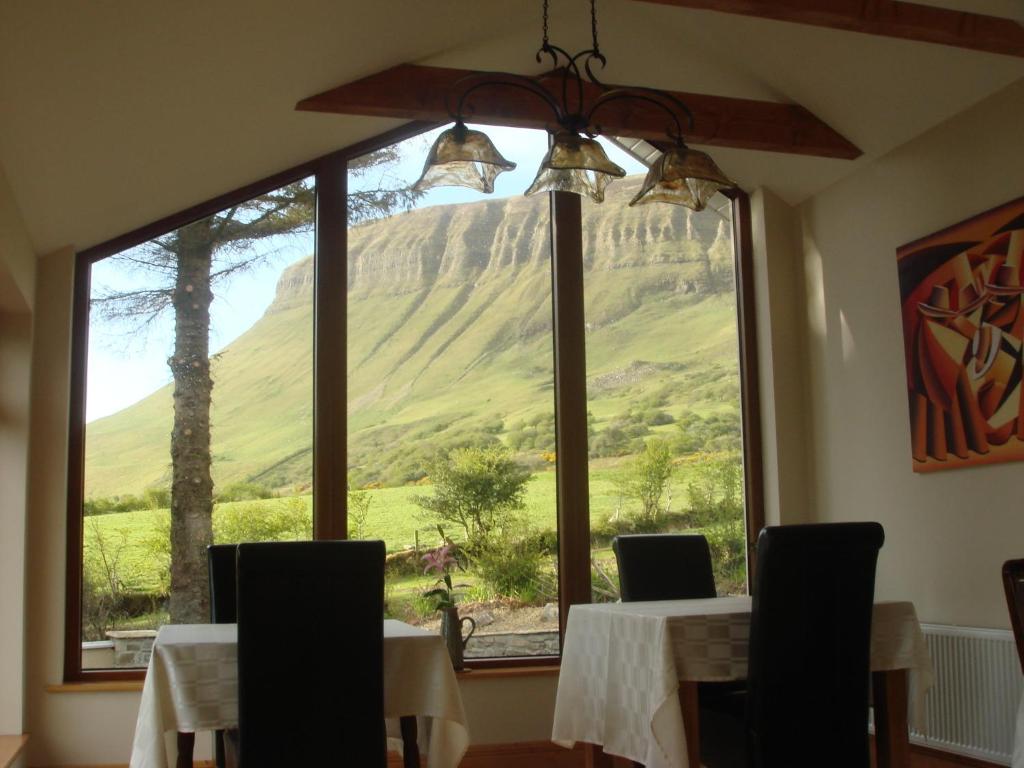a dining room with a view of a mountain through a window at Benbulben Farmhouse B&B in Drumcliff