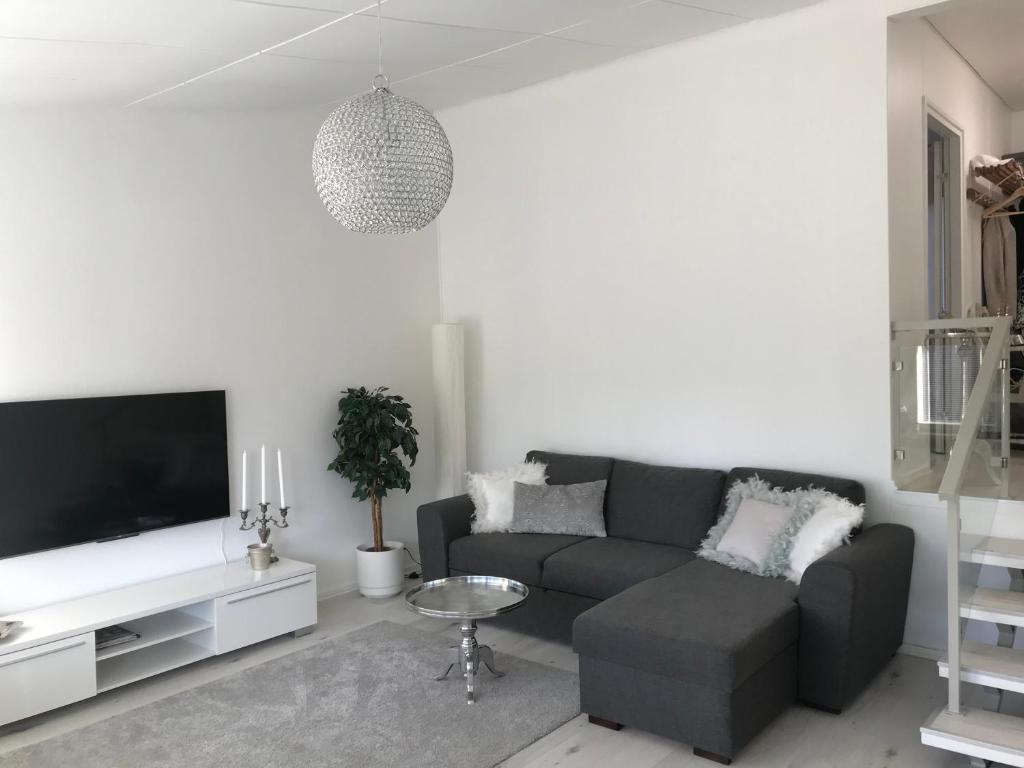 a living room with a gray couch and a tv at Tyylikäs rivitaloasunto Lohjalla in Lohja