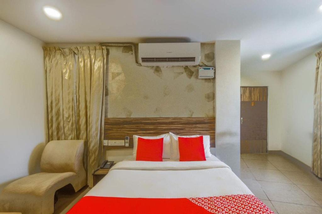 een slaapkamer met een bed met rode kussens en een stoel bij Serenity Inn in Chennai