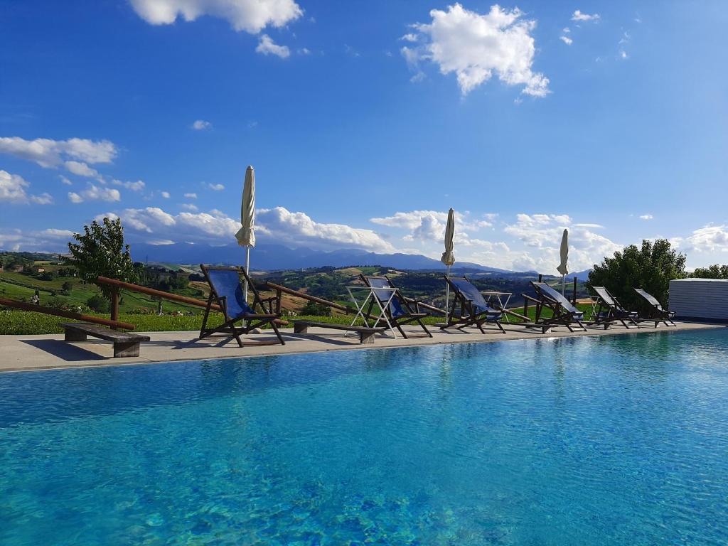 a swimming pool with chairs and umbrellas on top of it at Casa Azzurra in Loro Piceno