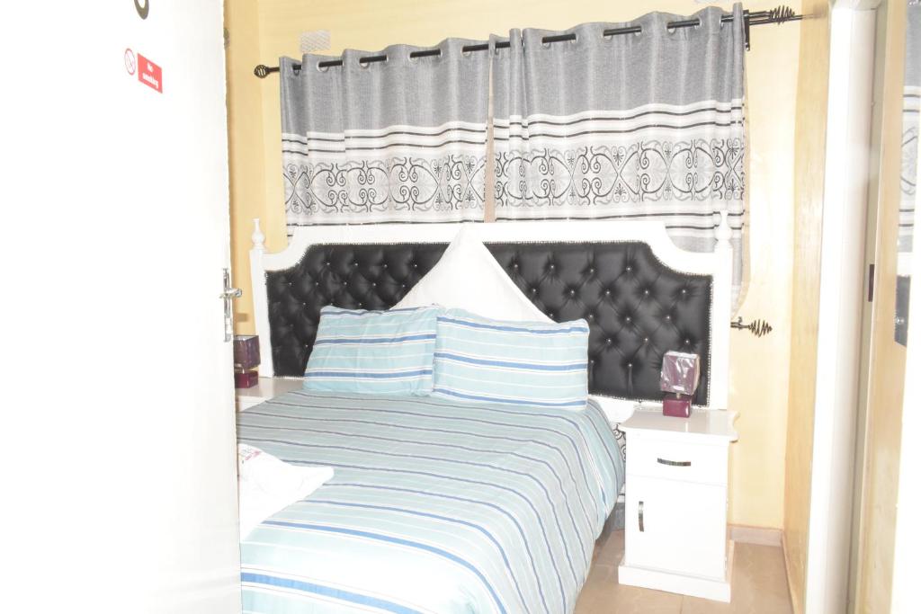 una camera con un grande letto con testiera nera di The Crown Inn Guest House a Harare