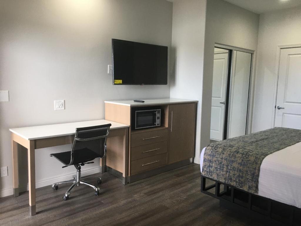 a hotel room with a bed and a desk with a computer at Cali Inn in Carson