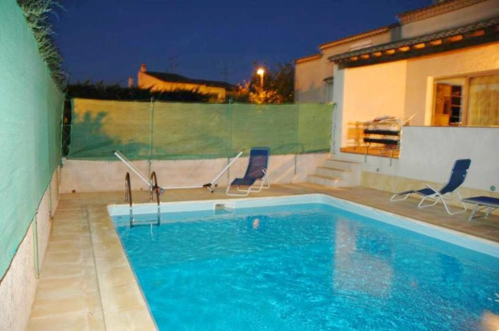 アグドにあるVilla de 3 chambres avec piscine privee et jardin clos a Agde a 2 km de la plageのスイミングプール(椅子2脚付)と家