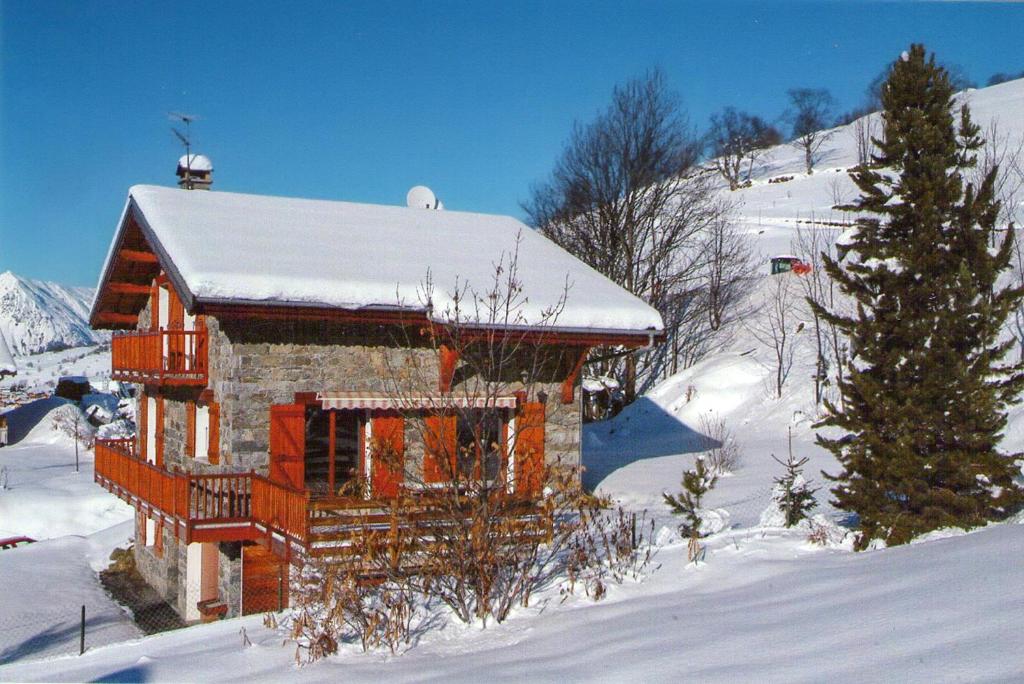 una cabaña de madera en la nieve con un árbol de Navidad en Chalet de 6 chambres avec jacuzzi jardin et wifi a Saint Martin de Belleville a 1 km des pistes en Praranger