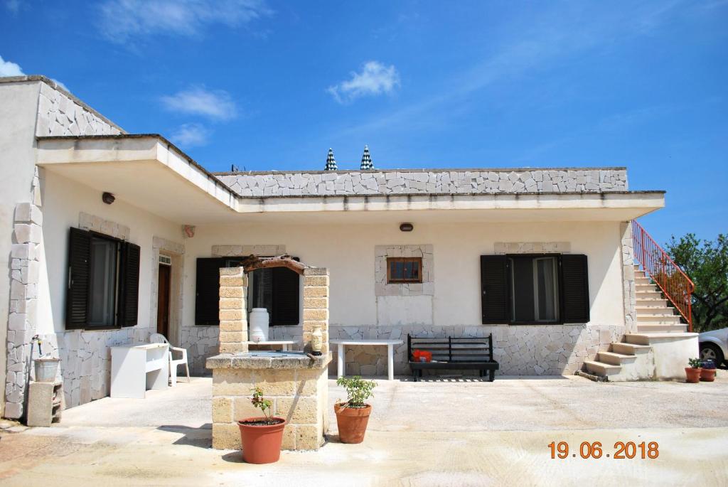 una piccola casa bianca con una panchina davanti di 2 bedrooms house with enclosed garden and wifi at Locorotondo a Locorotondo