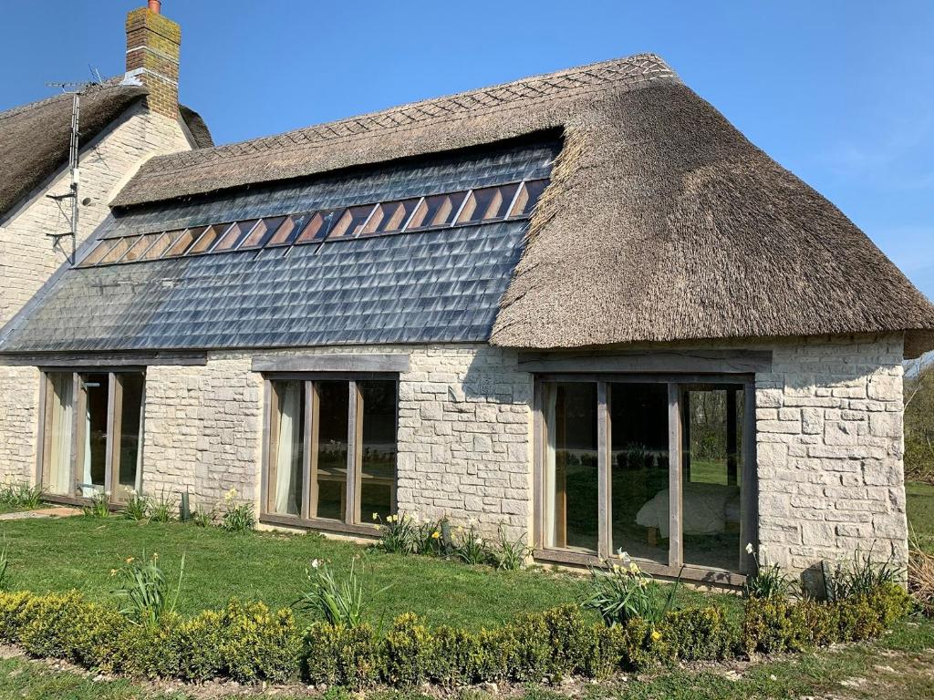 an old stone house with a thatched roof at Shortlake Cottage in Osmington