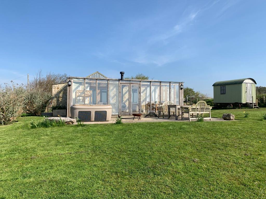 a large glass house with a picnic table in a field at The Old Lookout in Osmington