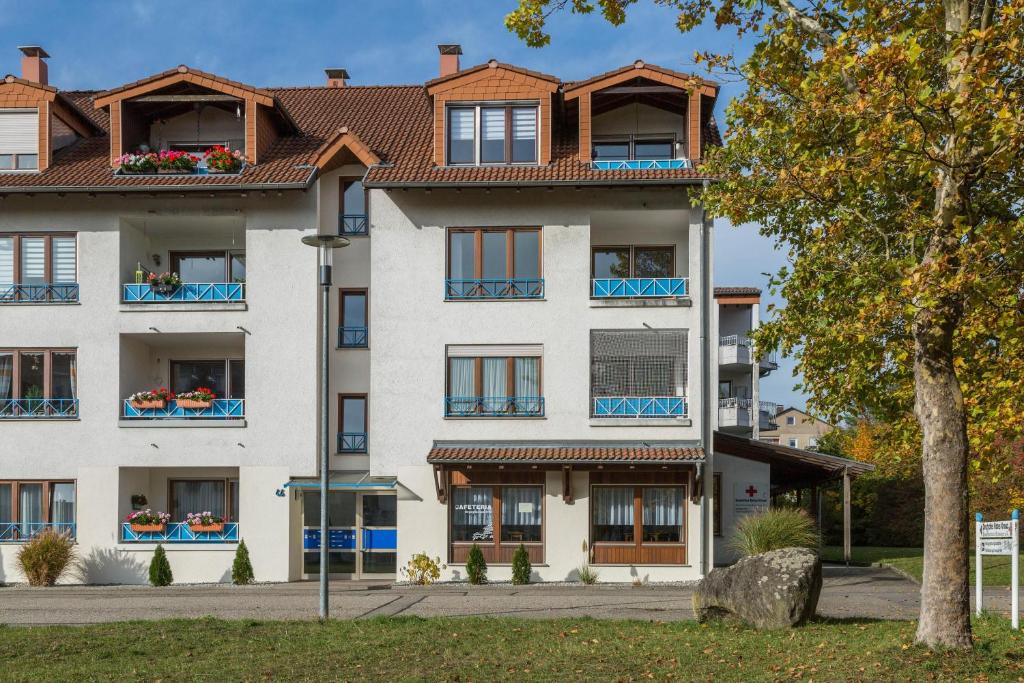 un grand bâtiment blanc avec des fenêtres et un arbre dans l'établissement Ferienwohnung Schlegel, à Singen