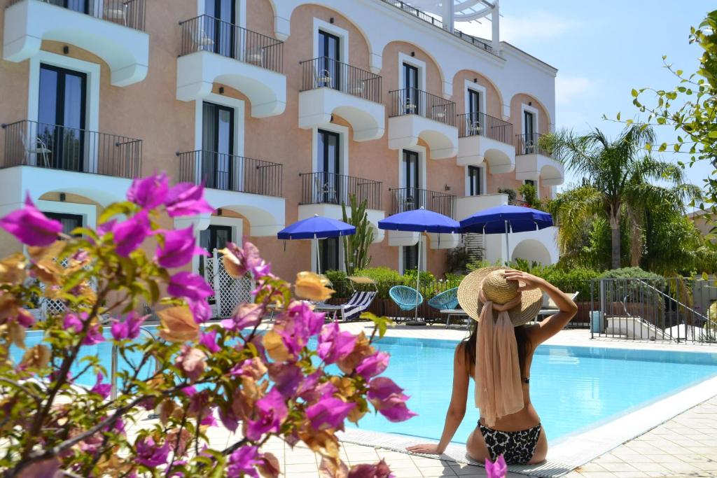 una mujer con sombrero sentada junto a una piscina en Hotel Murmann, en Maratea
