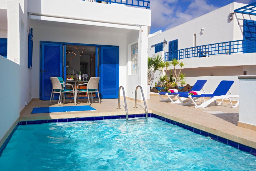 una villa con piscina, tavolo e sedie di VILLA DE LA CRUZ by Buenavilla a Playa Blanca