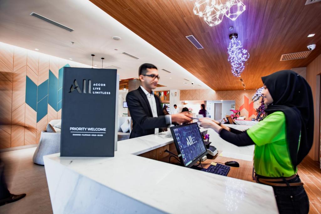 a man and a woman standing at a cash register at ibis Styles Kota Bharu in Kota Bharu