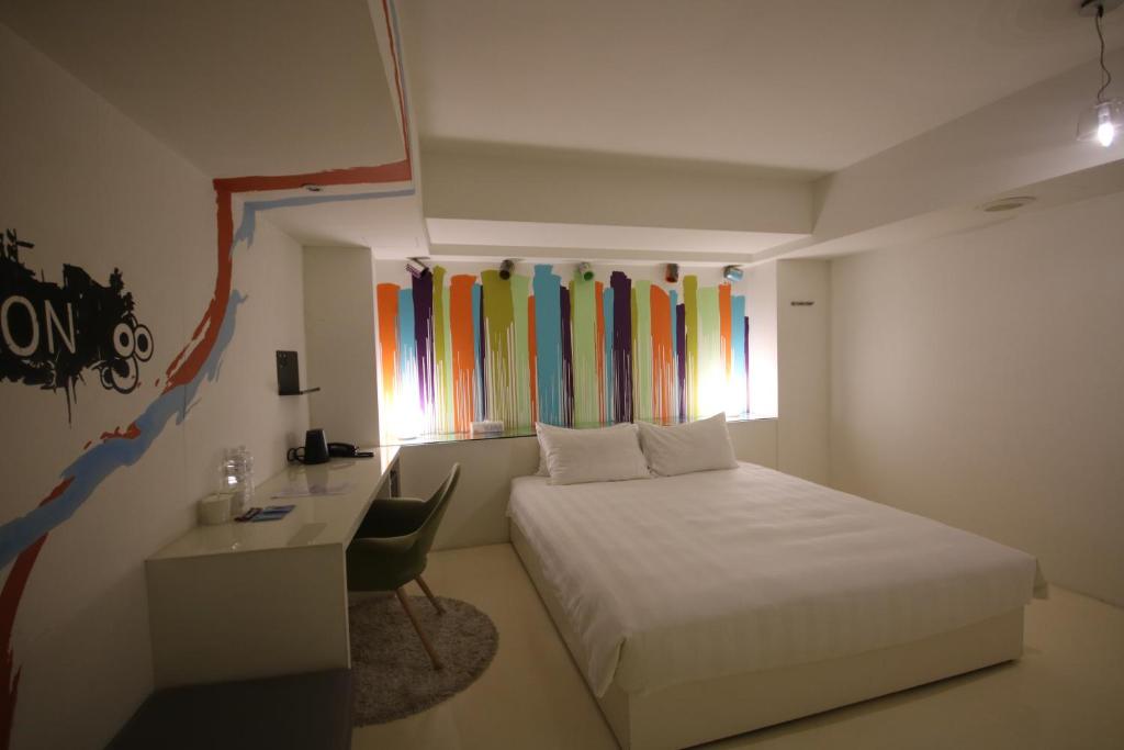 a bedroom with a bed and a desk and a window at Hotel Papa Whale-Kaohsiung Formosa Boulevard in Kaohsiung