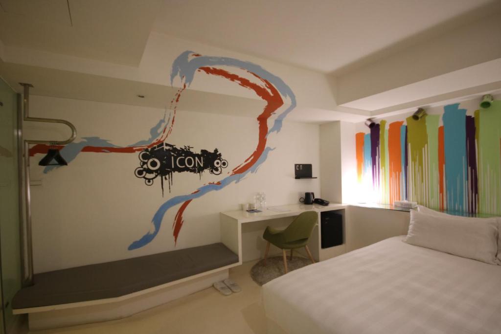a bedroom with a bed and a desk with a painting on the wall at Hotel Papa Whale-Kaohsiung Formosa Boulevard in Kaohsiung