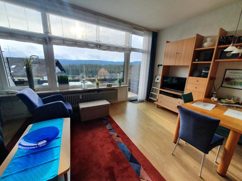 ein Wohnzimmer mit einem Tisch und Stühlen sowie einem großen Fenster in der Unterkunft Appartement mit Südbalkon im Haus Feldbergblick in Kappel - Appartement 37 in Lenzkirch
