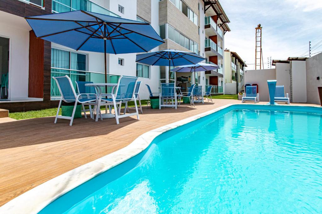 uma piscina com cadeiras e guarda-sóis ao lado de um edifício em Porto Sol by AFT - PORTO DE GALINHAS em Porto de Galinhas