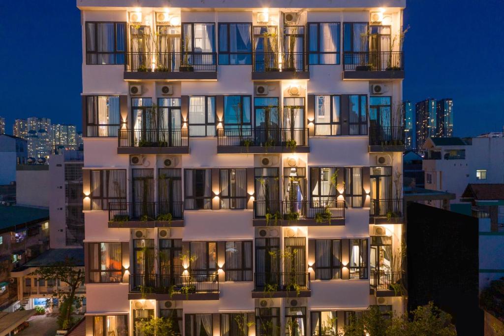ein hohes weißes Gebäude mit Balkonen in der Nacht in der Unterkunft KunKin Luxury Hotel & Apartment in Ho-Chi-Minh-Stadt
