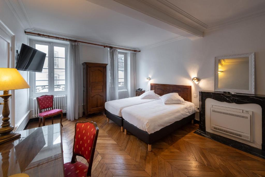 A bed or beds in a room at Hôtel des Tonneliers