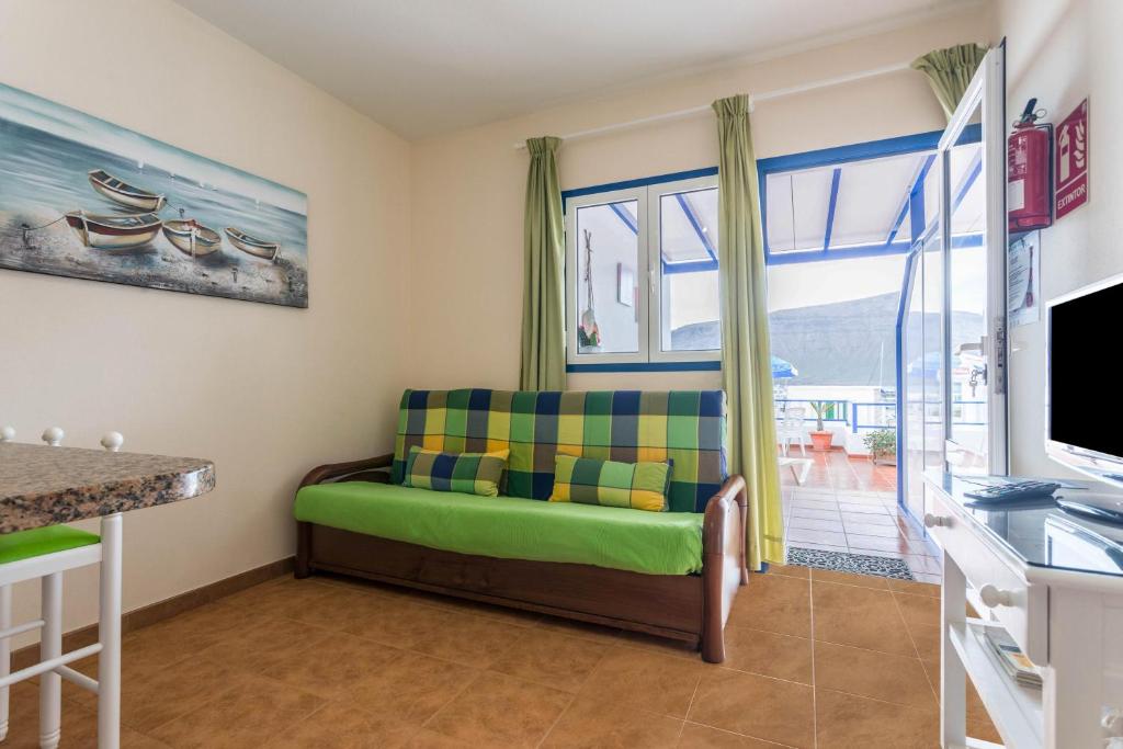ein Wohnzimmer mit einem grünen Sofa und einem Fenster in der Unterkunft El Sombrerito 5 in Caleta de Sebo