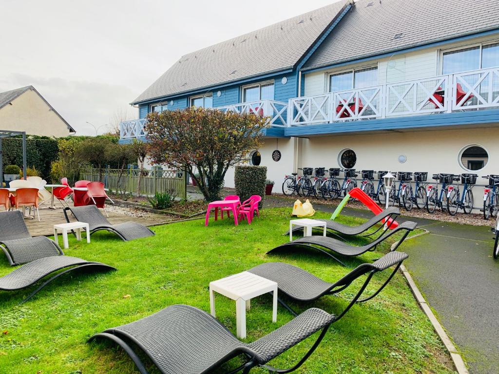 a row of lawn chairs and lawn chairs in front of a building at Contact hôtel - Motel Les Bleuets in Honfleur