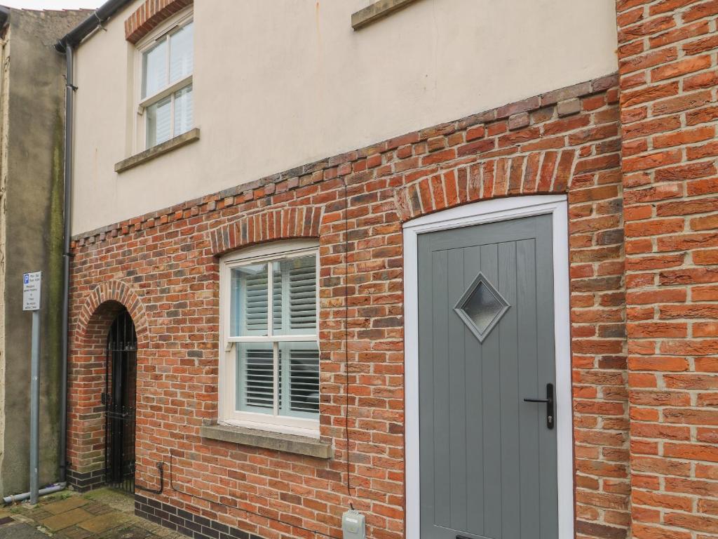 a brick building with a grey door and a window at Armstrong Cottage in Beverley