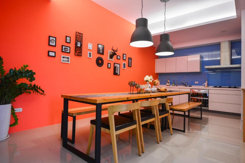 een keuken met een oranje muur en een tafel en stoelen bij Tainan Together House in Tainan